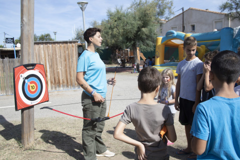 Een volwassene leert kinderen boogschieten op Seasonova Camping Barberousse, een vakantiepark in Frankrijk.