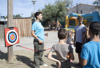 Een volwassene leert kinderen boogschieten op Seasonova Camping Barberousse, een vakantiepark in Frankrijk.