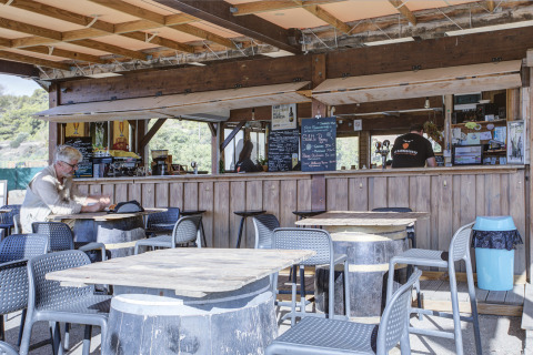 Buitenterras van Seasonova Camping Barberousse in Occitanië, Frankrijk, met tafels en een etende gast.