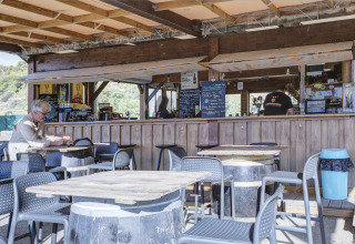 Buitenterras van Seasonova Camping Barberousse in Occitanië, Frankrijk, met tafels en een etende gast.