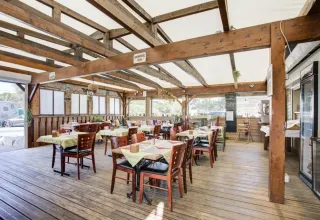 Overdekt eetgedeelte met houten balken en tafels in Seasonova Camping Barberousse, Occitanië, Frankrijk.