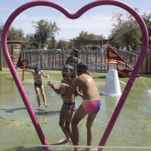 Kinderen spelen onder waterstralen in een hartvormig kader bij Seasonova Camping Barberousse in Occitanië.