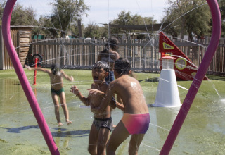 Børn leger under vandstråler i en hjerteformet ramme på Seasonova Camping Barberousse i Occitanie.