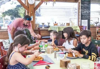 Kinderen eten samen aan een tafel bij Seasonova Camping Barberousse in Occitanië, Frankrijk.