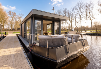 Houseboat moderno ad Offingawier con ampia terrazza esterna, vetrate e vista su acqua e alberi.