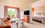 Modernes, helles Interieur im Tiny House XL bei De Kremmer, Niederlande, mit Sofa, Bett und Essbereich.