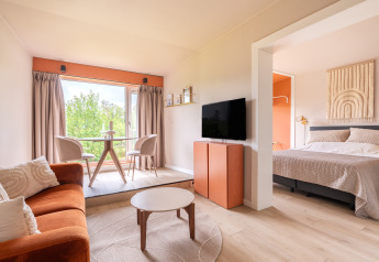 Modernes, helles Interieur im Tiny House XL bei De Kremmer, Niederlande, mit Sofa, Bett und Essbereich.