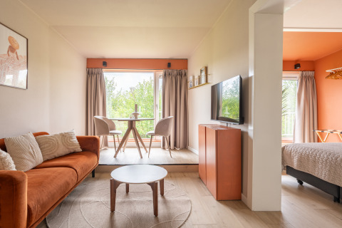 Lichte, moderne Tiny House XL bij De Kremmer, Nederland, met oranje accenten en grote ramen.