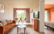 Modernes Tiny House XL bei De Kremmer, Niederlande, mit heller Einrichtung, Sofa und großem Fenster.