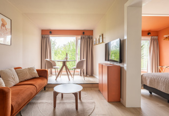 Modernes Tiny House XL bei De Kremmer, Niederlande, mit heller Einrichtung, Sofa und großem Fenster.