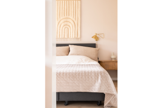 Cozy bed in Tiny House XL at De Kremmer, Netherlands, featuring modern neutral décor and soft lighting.