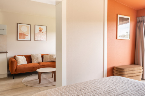 Licht en modern interieur in Tiny House XL bij De Kremmer, met oranje bank en wanddecoratie.