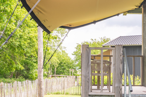 View from the terrace of Tiny House XL at De Kremmer in the Netherlands, showing wooden fence and greenery.