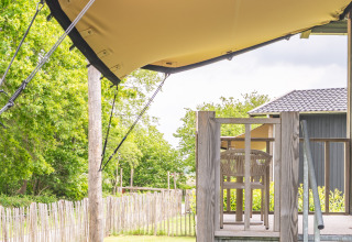 Uitzicht vanaf het terras van Tiny House XL bij De Kremmer in Nederland, met houten hek en groen.