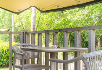 Gemütliche Veranda mit Tisch und Stühlen, umgeben von Holzgeländer und grüner Natur bei De Kremmer, NL.