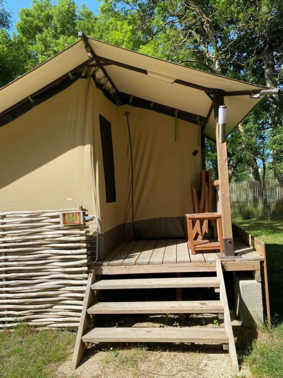 Safaritent Lodge Balearic bij Camping les Rives de Grand Lieu in Frankrijk met houten terras en stoel.