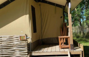 Tenda safari Lodge Balearic al Camping les Rives de Grand Lieu in Francia, con veranda in legno e sedia.