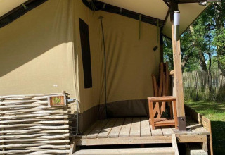 Tenda safari Lodge Balearic al Camping les Rives de Grand Lieu in Francia, con veranda in legno e sedia.