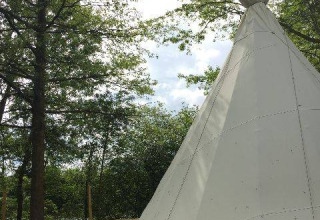 Grande tenda tipi su pedana in legno circondata da alberi al Camping les Rives de Grand Lieu in Francia.