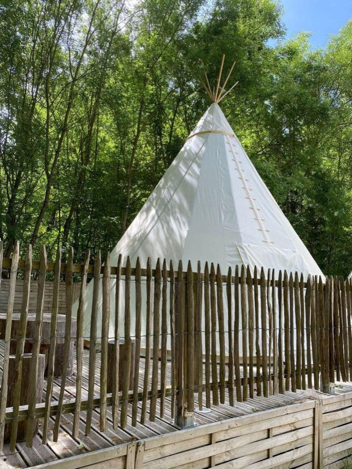 Tipitent op Camping les Rives de Grand Lieu in Frankrijk, omringd door bomen en een houten omheining.