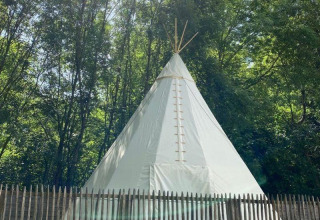 Una tenda tipi bianca al Camping les Rives de Grand Lieu in Francia, circondata da alberi e staccionata.