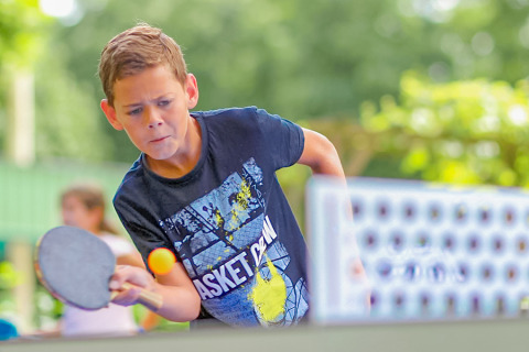 Ein Junge spielt Tischtennis im Camping Paradis Le Giessen, einem Ferienpark in Grand Est, Frankreich.