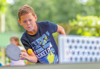 Un niño jugando al ping pong en Camping Paradis Le Giessen, un parque de vacaciones en Grand Est, Francia.