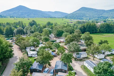 Feriepark Camping Paradis Le Giessen i Grand Est, Frankrig, med mobilhomes, natur og bjerge i baggrunden.