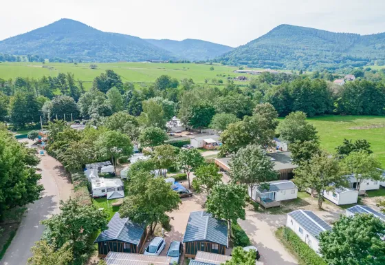 Feriepark Camping Paradis Le Giessen i Grand Est, Frankrig, med mobilhomes, natur og bjerge i baggrunden.