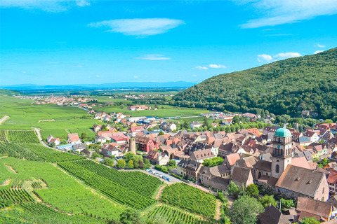 Vista panoramica su Bassemberg in Grand Est, Francia, con vigneti, colline verdi e case tipiche del villaggio.