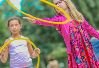 Dos niñas juegan con aros amarillos en el parque de vacaciones Camping Paradis Le Giessen en Grand Est, Francia.