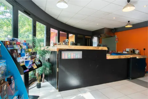 Onthaal Camping Paradis Le Giessen, Grand Est, Frankrijk met zwarte balie en rek met folders.