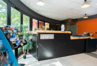 Recepción en Camping Paradis Le Giessen, Grand Est, Francia, con mostrador negro y folletos turísticos.