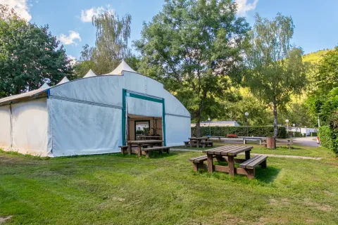 Picknicktafels en een grote witte tent bij Camping Paradis Le Giessen, vakantiepark in Grand Est, Frankrijk.