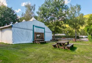 Tavoli da picnic all'aperto e grande tenda bianca al Camping Paradis Le Giessen, parco vacanze in Grand Est, Francia.
