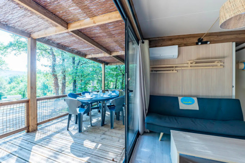 Interior luminoso con terraza y vista al bosque en Cottage Premium 3, Camping Paradis Le Giessen, Francia.