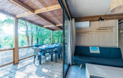 Interior luminoso con terraza y vista al bosque en Cottage Premium 3, Camping Paradis Le Giessen, Francia.