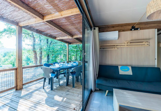 Interior luminoso con terraza y vista al bosque en Cottage Premium 3, Camping Paradis Le Giessen, Francia.