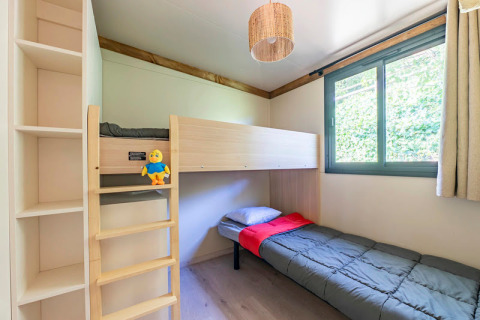 Habitación luminosa en Cottage Premium 3 del Camping Paradis Le Giessen, con litera y ventana grande.