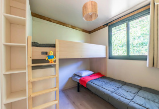 Habitación luminosa en Cottage Premium 3 del Camping Paradis Le Giessen, con litera y ventana grande.