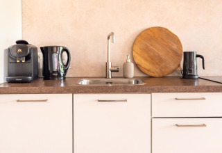 Moderne kitchenette in Tiny House XL bij De Kremmer, Nederland, met koffiezetapparaat en waterkokers.