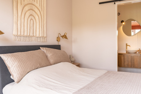 Lichte, knusse slaapkamer in Tiny House XL bij De Kremmer, Nederland, met moderne warme inrichting en badkamer.