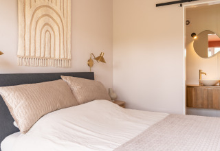 Lichte, knusse slaapkamer in Tiny House XL bij De Kremmer, Nederland, met moderne warme inrichting en badkamer.
