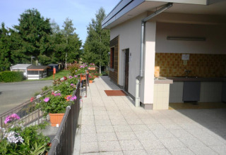 Udsigt over det udendørs køkkenområde og blomsterprydede terrasse på Onlycamp Camping l'Orée d'Alsace.