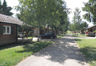 Cabañas de madera y un coche en Onlycamp Camping l'Orée d'Alsace, parque vacacional en Grand Est, Francia.