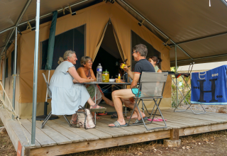 Quatre personnes discutent devant une tente safari au Onlycamp Camping l'Orée d'Alsace en France.