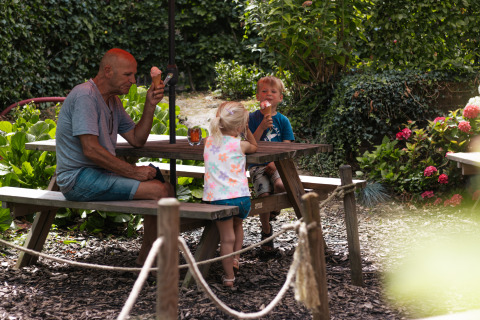 Man en twee kinderen genieten van ijsjes aan tafel bij Safari Trekking tent op Camping 't Geuldal in Nederland.