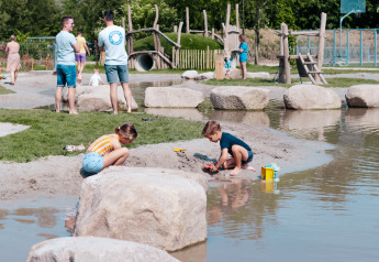 Bambini che giocano vicino a uno stagno in un'area giochi all'aperto a Camping 't Geuldal, Paesi Bassi.