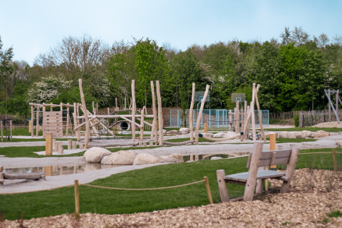 Natuurspeeltuin met houten klimelementen en basketbalveld bij Camping 't Geuldal, Nederland.