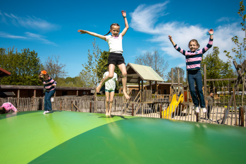 Kinderen spelen op een springkussen bij een Safari Trekking tent op Camping 't Geuldal in Nederland.